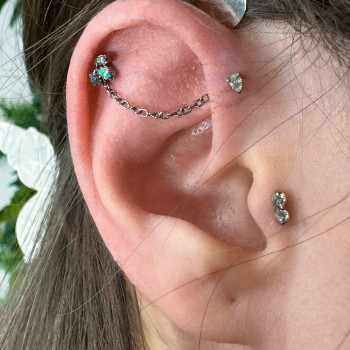 Пірсинг форвард хелікс та хелікс, поєднанні титановим ланцюжком. У проколи встановленні накрутки з к...