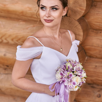 Стильный портрет невесты у деревянной стены: легкая улыбка, аккуратный макияж и букет с лиловыми акцентами и лентами. Свадебный фотограф в Днепре — чистый кадр, красивые цвета и внимание к деталям., фото - фотограф Дмтрий Покидин
