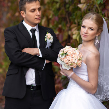 Сдержанный портрет молодоженов на фоне осенних листьев: невеста с нежным букетом и фатой, жених в классическом костюме., фото - фотограф Дмтрий Покидин