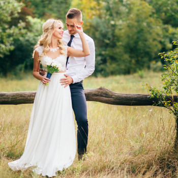 Легкая летняя прогулка молодоженов на природе: объятия возле деревянного забора, искренняя улыбка и букет в руках невесты. Свадебный фотограф в Днепре — живые кадры без лишнего позирования, естественный свет и теплая атмосфера, фото - фотограф Дмтрий Поки