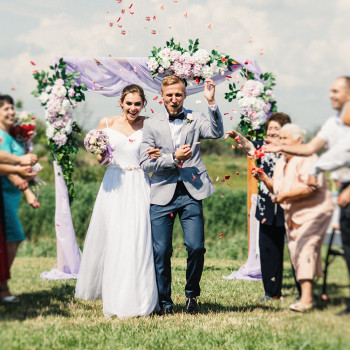 Выездная церемония на природе: молодожены выходят из-под цветочной арки под лепестками, вокруг радостные гости и настоящие эмоции. Свадебный фотограф в Днепре – репортаж церемонии, живые моменты и красивый декор в кадре., фото - фотограф Дмтрий Покидин