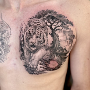 Тату на грудях: тигр у природному пейзажі з деревом, чорно-сірий реалізм.