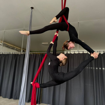Учениця студії TrioDance виконує красивий трюк на повітряних полотнах.