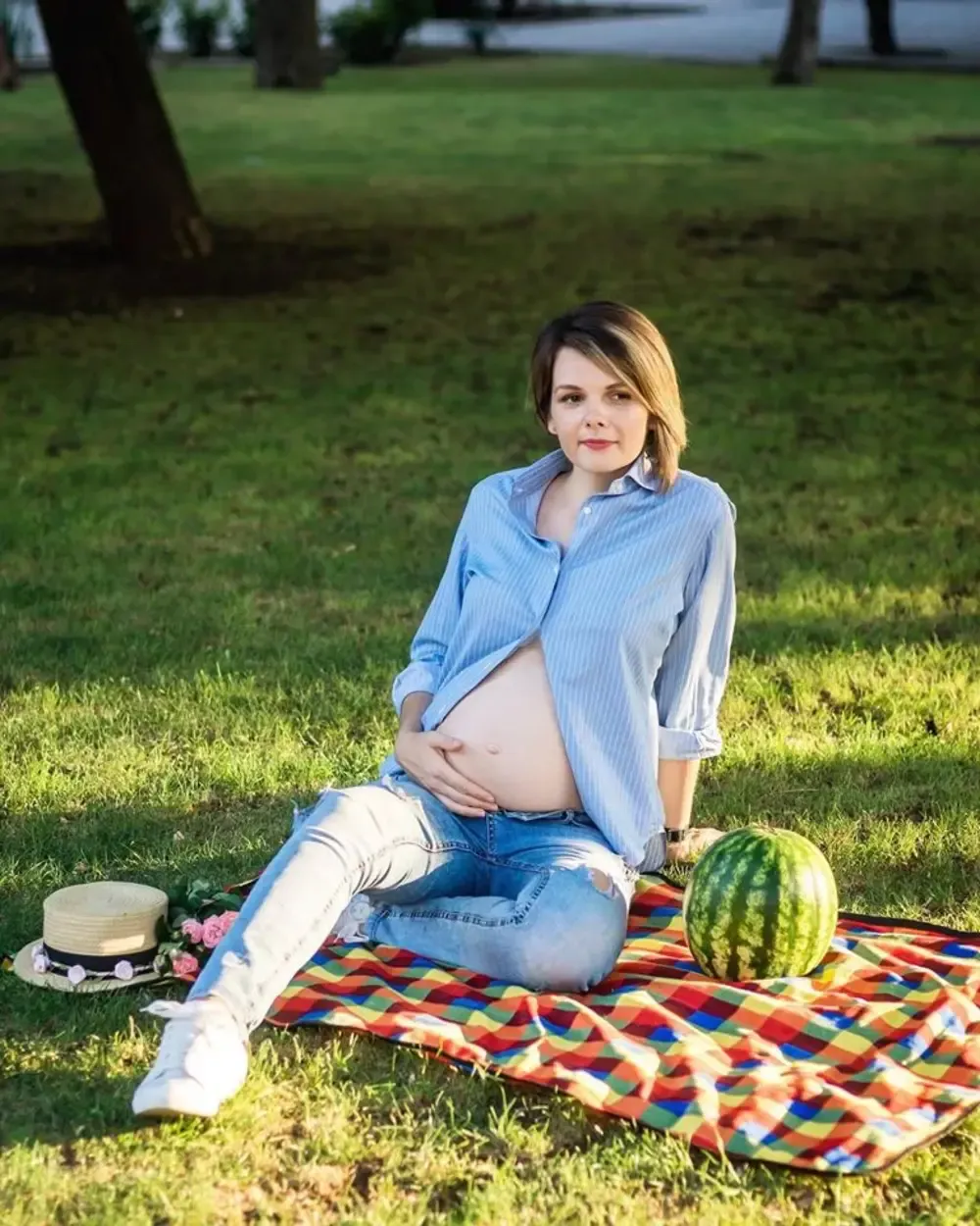 Креативна фотосесія вагітності на пікніку з кавуном у розстебнутій блакитній сорочці